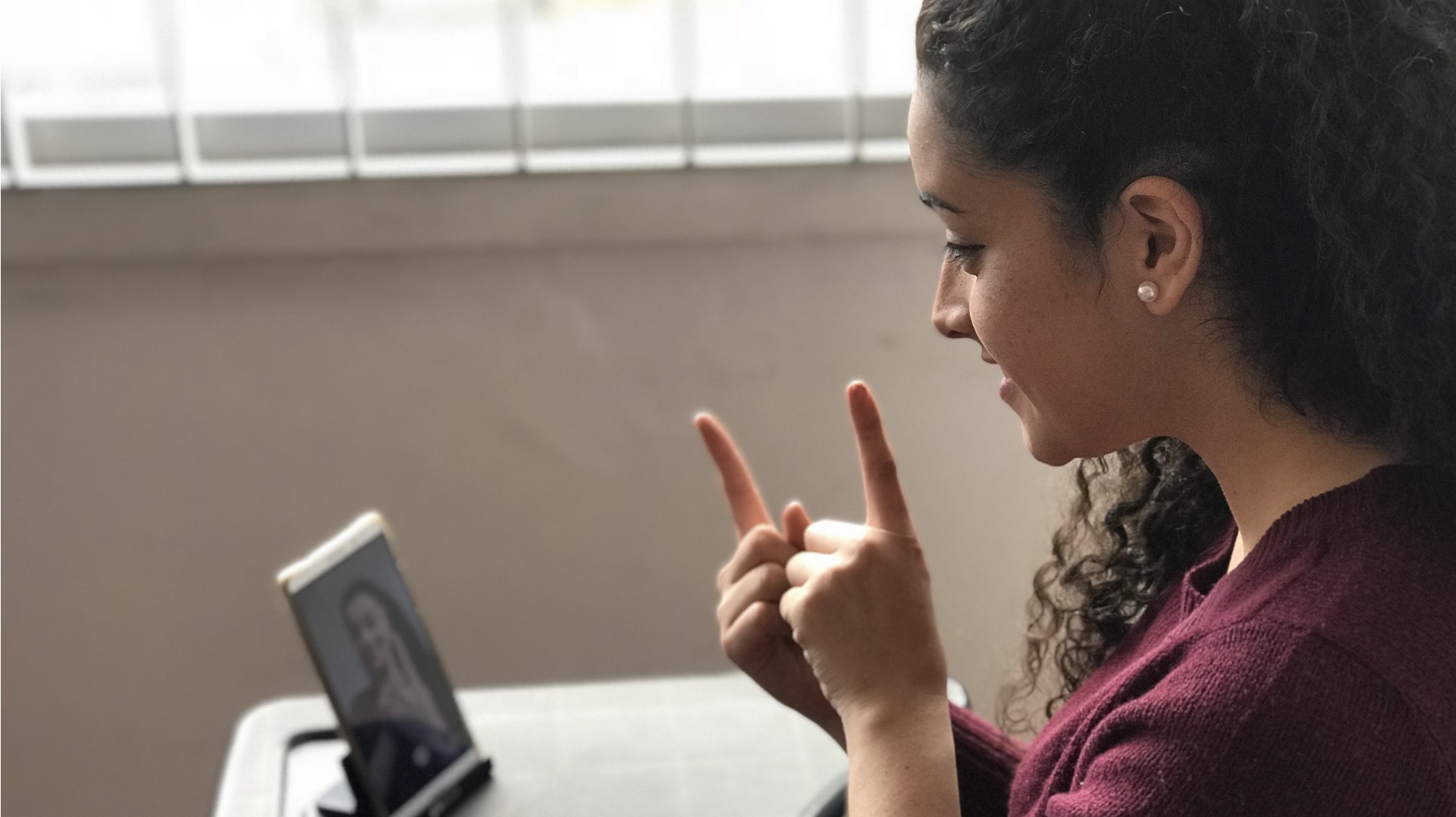 Fotografía: Mujer frente a un teléfono celular usando lengua de señas